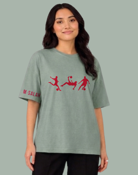 Person wearing a green t-shirt with red graphics and text on a gray background