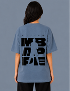 Person wearing a blue t-shirt with a graphic design on the back against a gray background