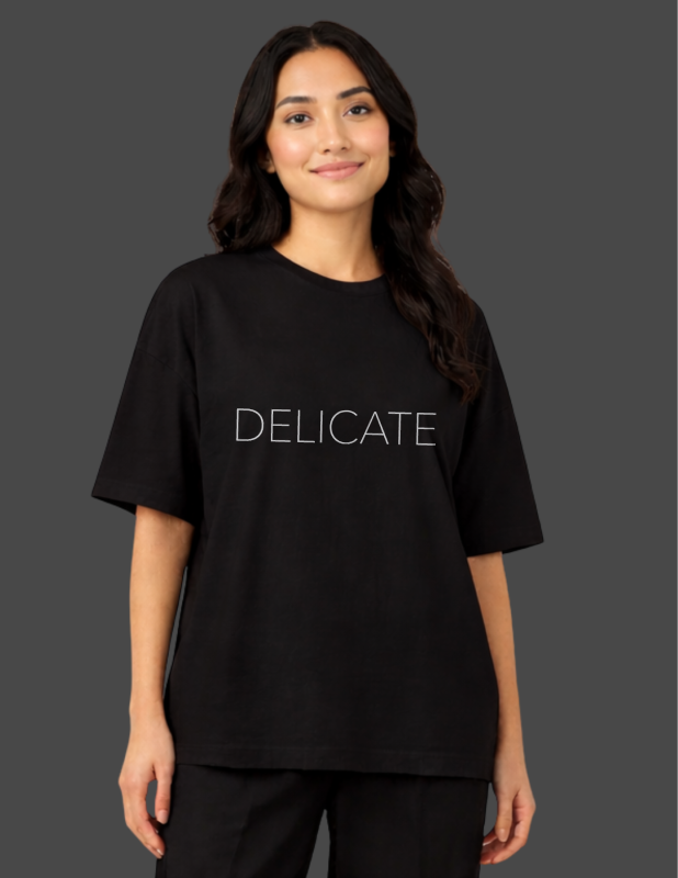 Person wearing a black t-shirt with 'DELICATE' text on a dark background