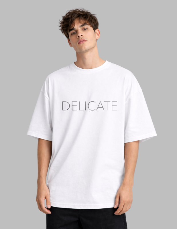 Person wearing a white t-shirt with 'DELICATE' text on a gray background