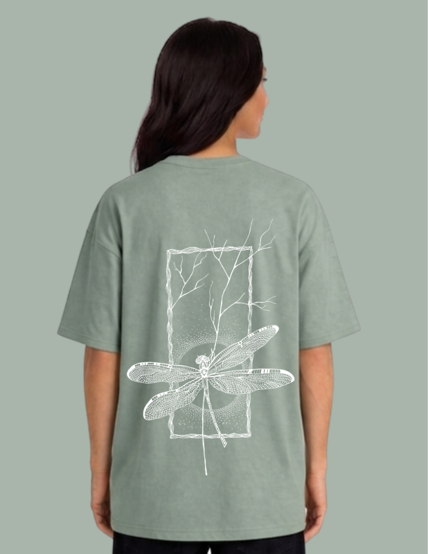 Person wearing a green t-shirt with a white dragonfly design on the back against a gray background