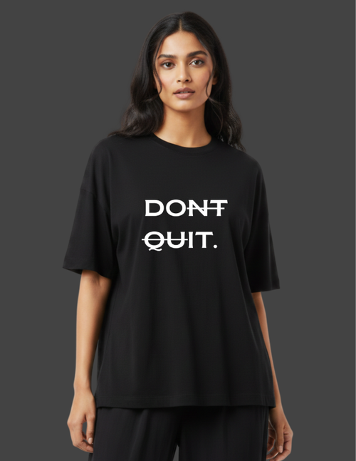 Person wearing a black t-shirt with 'DON'T QUIT.' text on a dark background