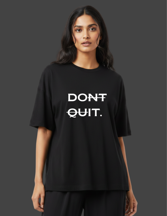 Person wearing a black t-shirt with 'DON'T QUIT.' text on a dark background