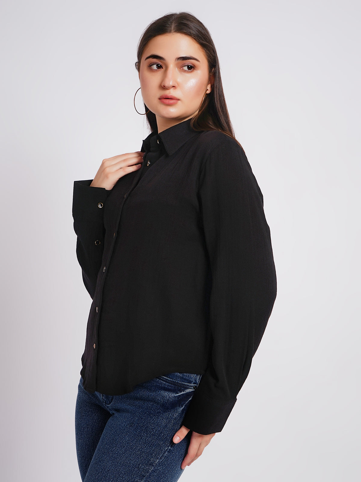 Woman wearing a black shirt and blue jeans on a plain background