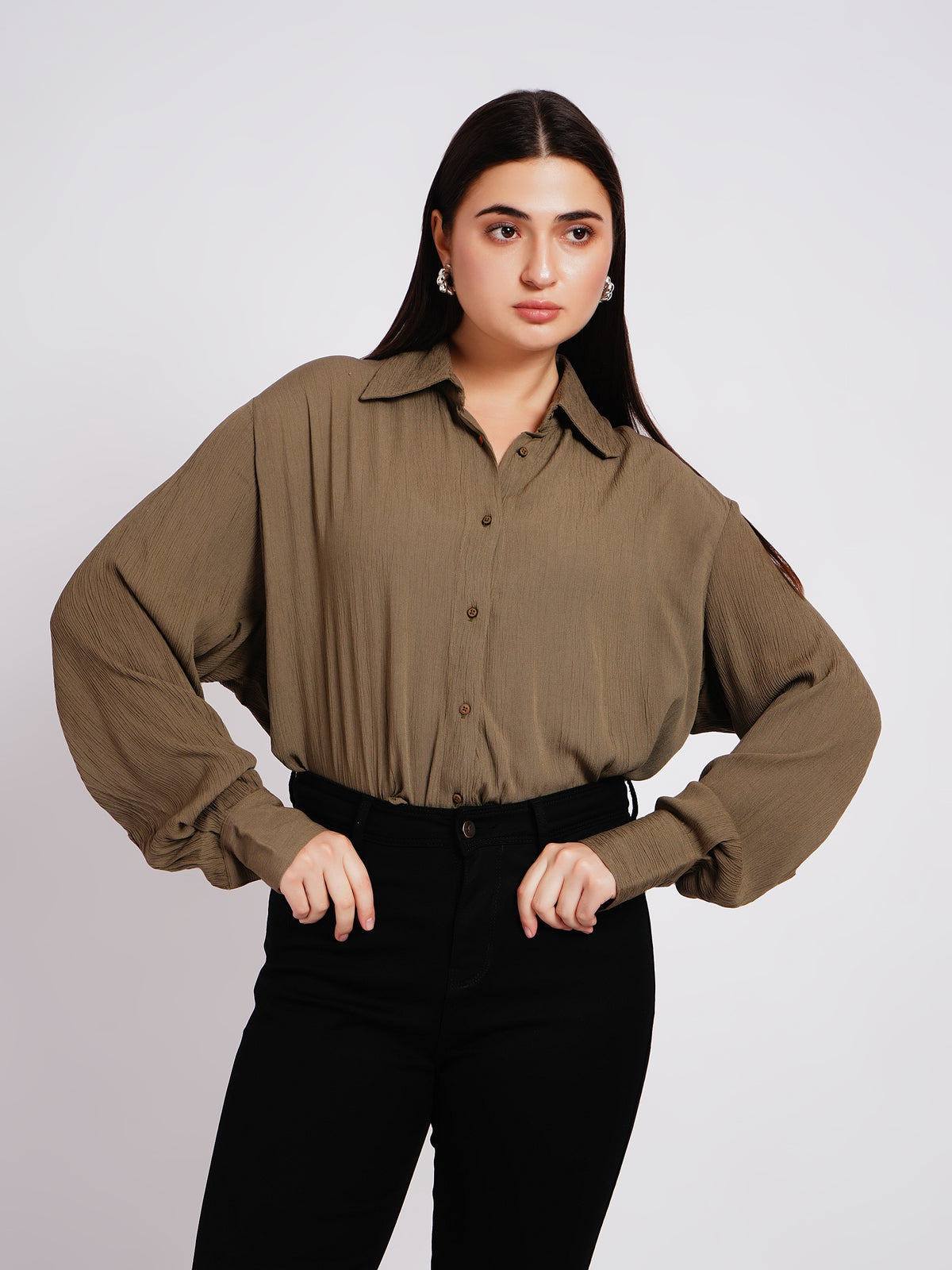Woman wearing a brown blouse and black pants on a white background